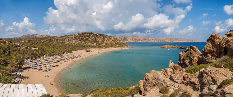 Panorama over Vai sandstrand med parasoller og bukt