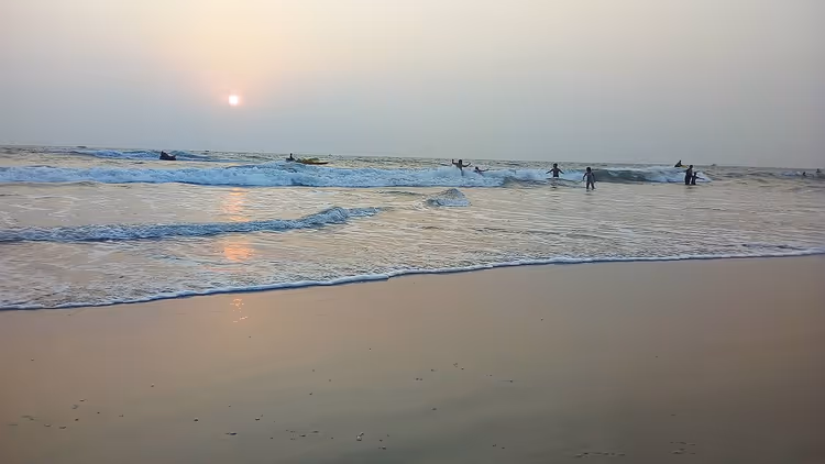 Varca Beach bij zonsondergang met golven en zwemmers
