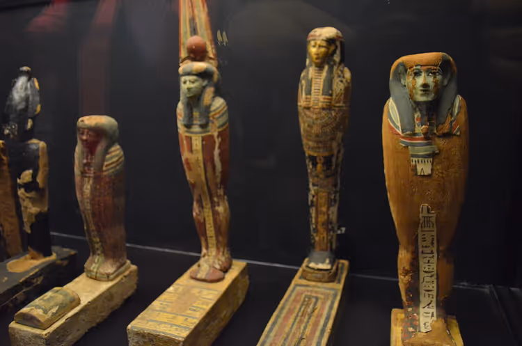 Bemalte ägyptische Holzfiguren in einer Museumsvitrine