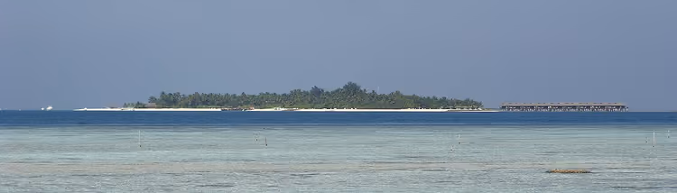 Resorteiland met bungalows boven een turquoise lagune