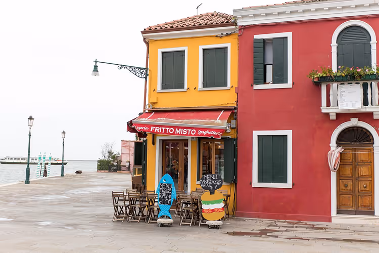 Fargerike hus og kafeer ved vannkanten på Burano