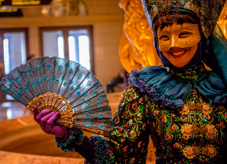 Person mit venezianischer Maske und Kostüm mit Fächer
