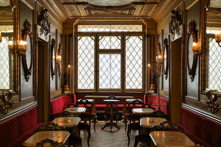 Interieur van Caffè Florian met spiegels en rode sofa's