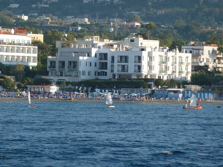 Zandstrand op Ischia met hotels en zeilboten