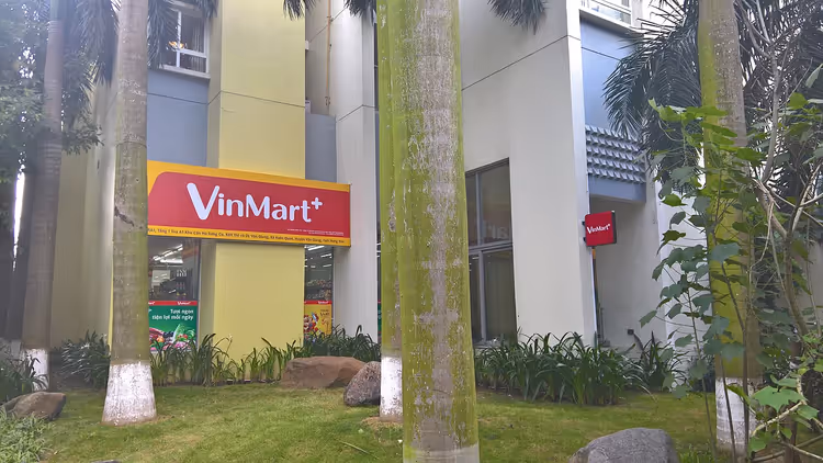 VinMart+ supermarkedsfasade blant palmer i Vietnam