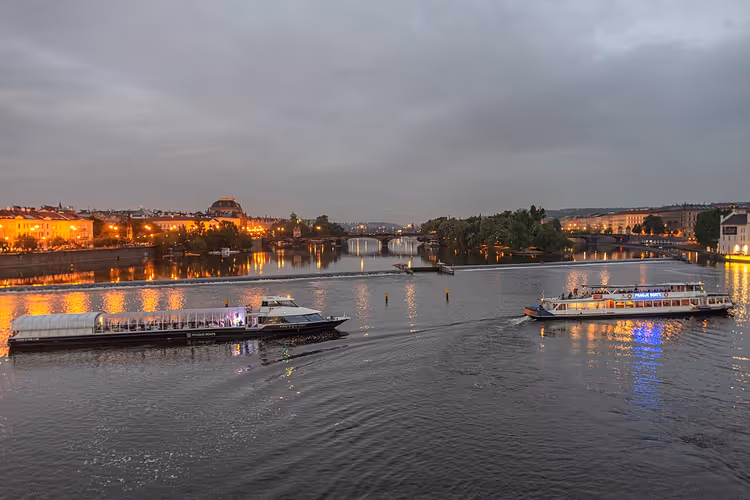 Verlichte rivierboten op de Vltava in de schemering van Praag