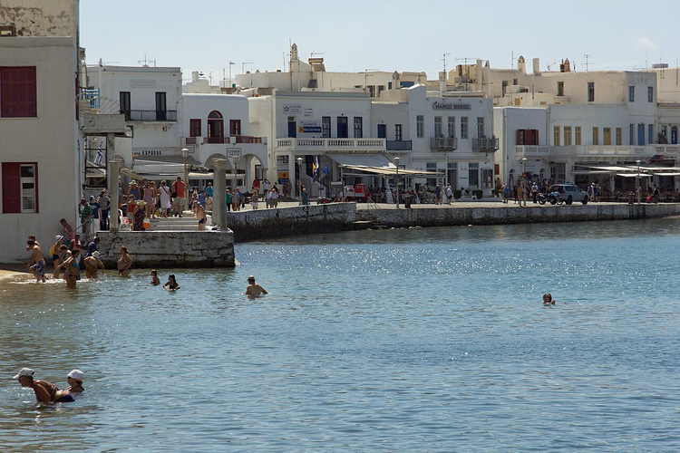 El paseo marítimo de Chora en Miconos, con gente bañándose en la orilla