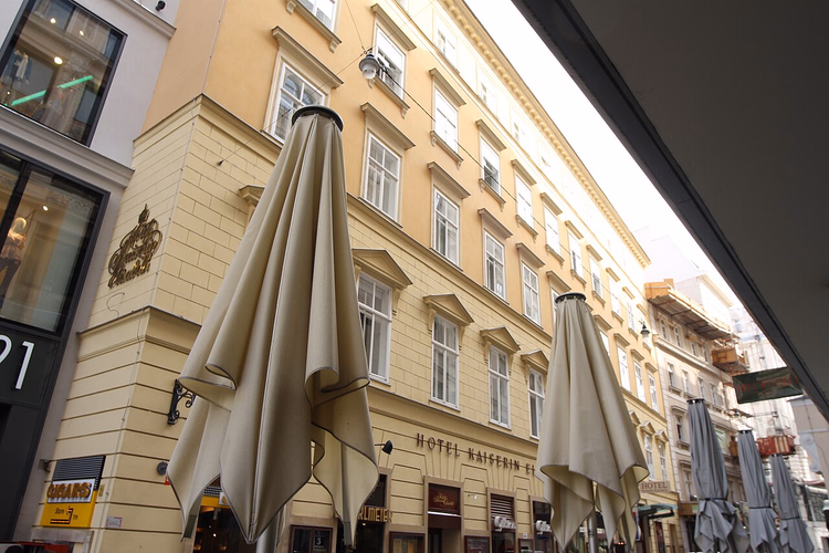 Gul hotellfasade i Weihburggasse med paraplyer