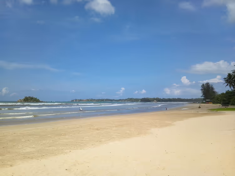 Zandstrand van Weligama met oceaan en palmbomen