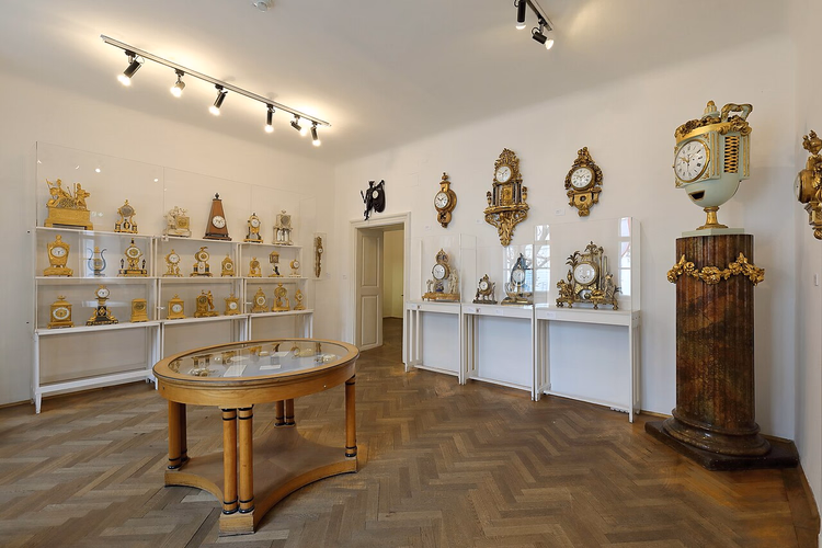 Zaal met vergulde antieke klokken in vitrines