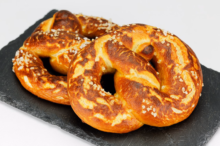 Twee pretzels met grof zout op een leien plank