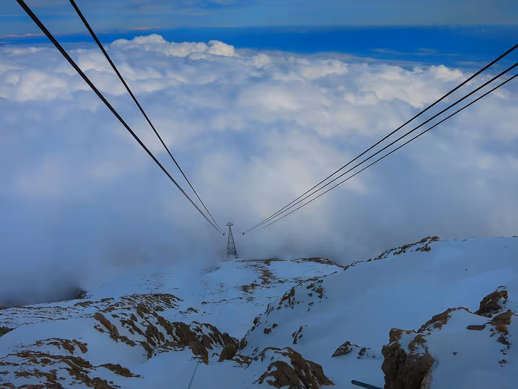 Seilbahnlinien über den Wolken auf einem schneebedeckten Berg