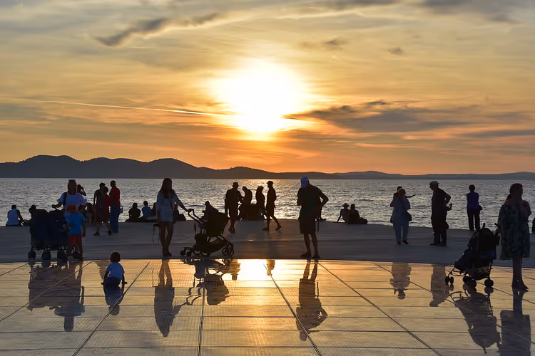 Sonnenuntergang an der Uferpromenade von Zadar mit Silhouetten von Menschen
