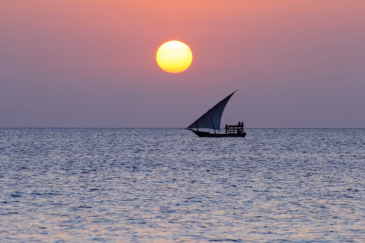 Zonsondergang boven de oceaan met een zeilende dhow