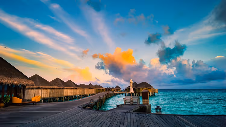 Tropisch resort met bungalows op het water bij zonsondergang