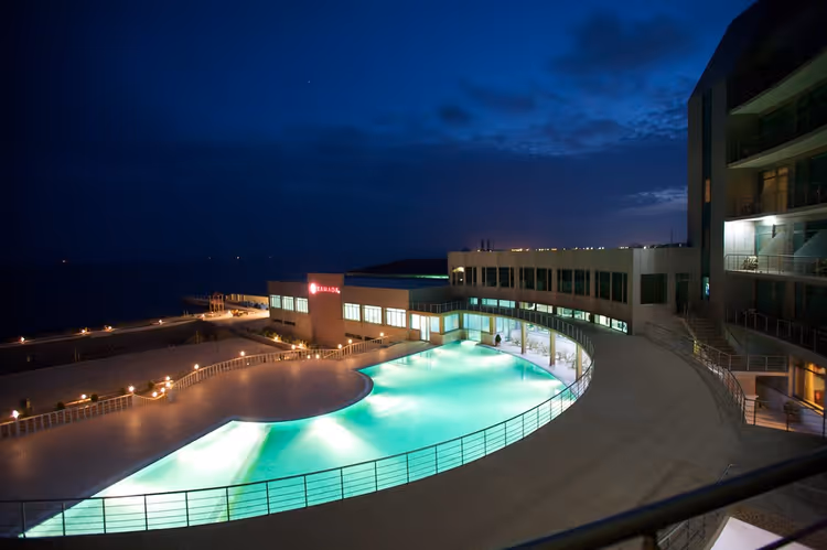 Deniz kenarında gece havuzu ve otel binası