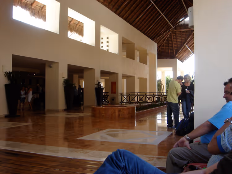 Ruime hotellobby met rieten daken en receptiebalie