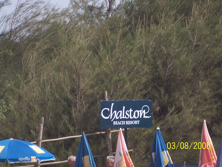 Schild des Chalston Beach Resort zwischen Büschen und Sonnenschirmen