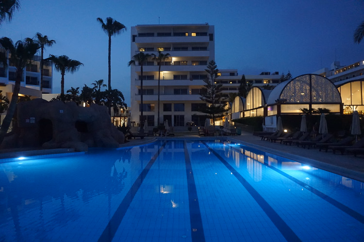 Hotellbygning og opplyst basseng om kvelden