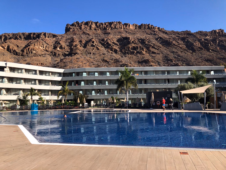 Arka planda kayalık dağlar bulunan tatil oteli havuzu