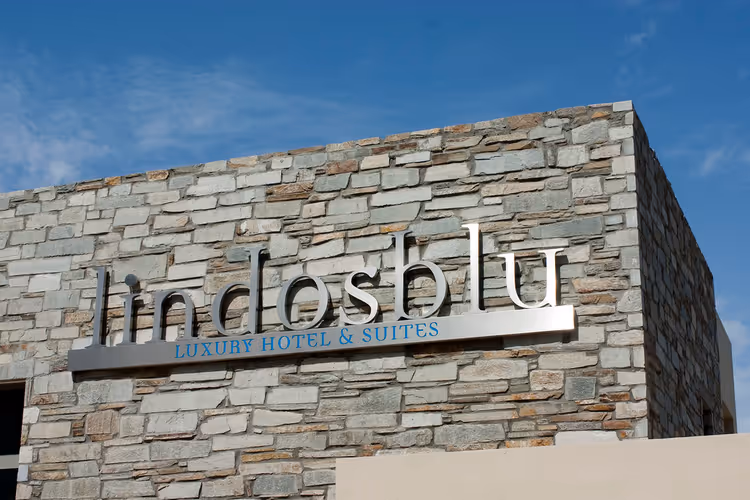 لافتة Lindos Blu على جدار حجري لفندق