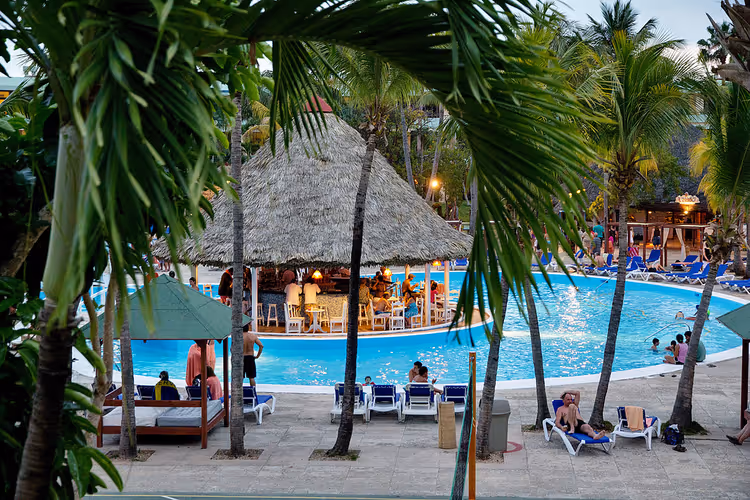 Zwembad van Sol Palmeras resort met palmbomen en ligstoelen