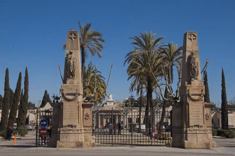 Monumentale porter ved Poblenou kirkegård med pyloner og palmer