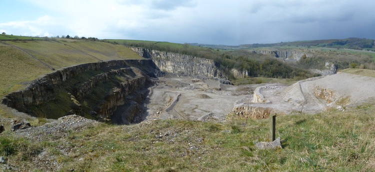 Panorama over et kalkbrudd blant grønne åser