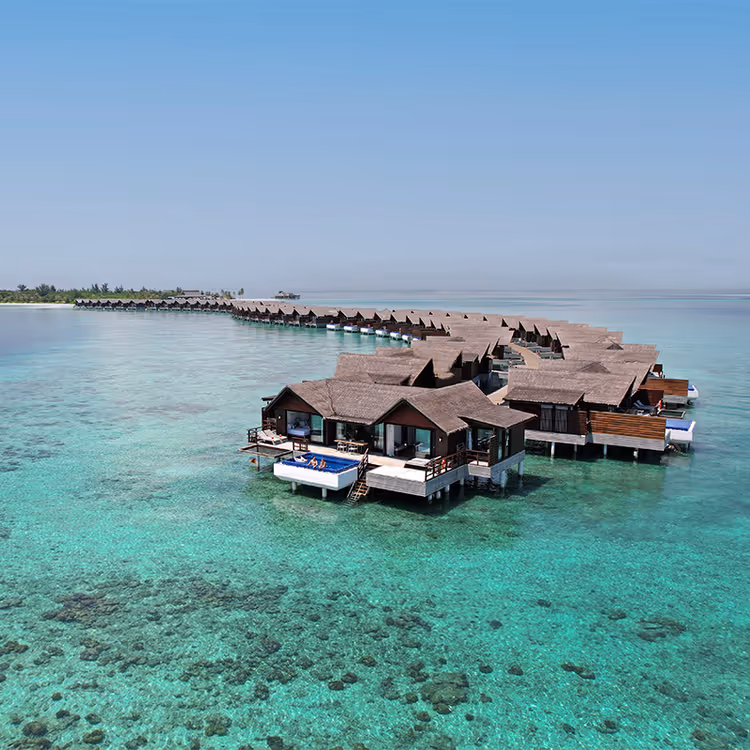 Villas op het water in een turquoise lagune bij een Maldivisch resort
