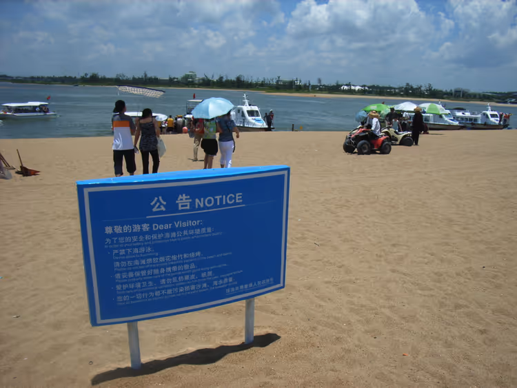 Strand met een blauw informatiebord en badgasten