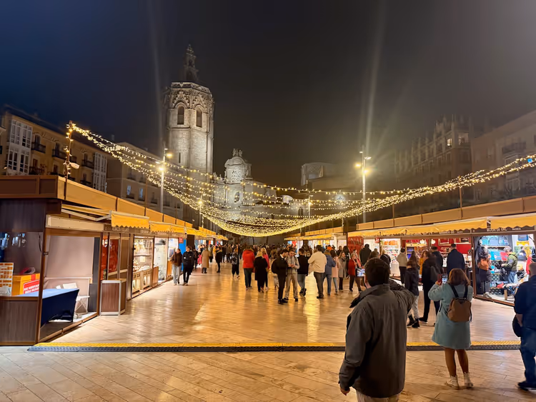 Praça da Rainha à noite com um mercado de Natal e a torre do Miguelete