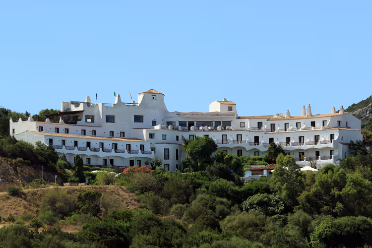 yeşilliklerle çevrili bir tepede beyaz tatil oteli