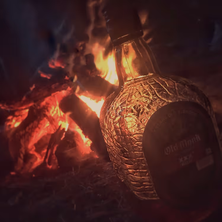 Fles Old Monk rum bij een brandend kampvuur
