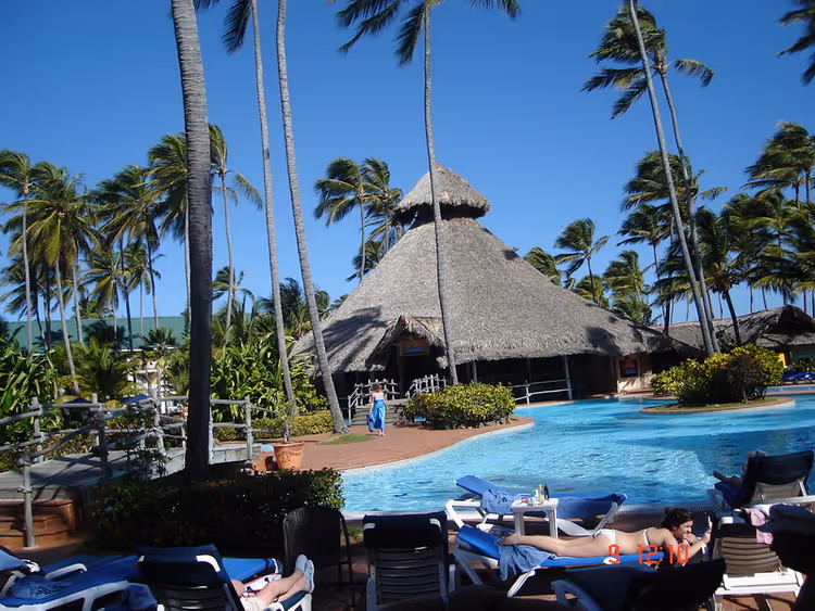 Barcelo Bavaro resortbasseng med palmer og stråtak