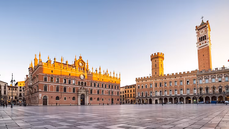 Illustration: weiter, leerer Pflasterplatz in Bologna mit roten Backsteinpalästen, Arkaden und zwei mittelalterlichen Türmen