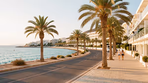 Von Palmen gesäumte Uferstraße und Promenade mit weißen Apartmenthäusern und zwei Spaziergängern, Symbolbild für Ayia Napa