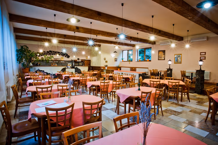 Eetzaal van een restaurant met gedekte tafels en houten balken
