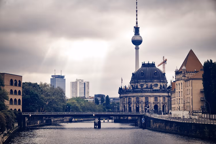 Bode-Museum mit Kuppel an der Spree, dahinter ragt der Fernsehturm in den grauen Himmel über Berlin