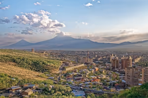 Dächer und Wohnblöcke von Jerewan im Abendlicht, am Horizont die beiden Gipfel des Ararat