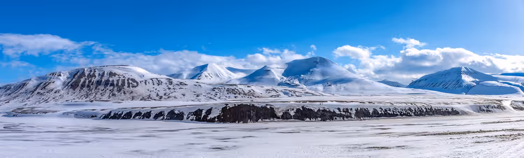 Panorama verschneiter Berge und einer gefrorenen Ebene unter tiefblauem Himmel auf Spitzbergen