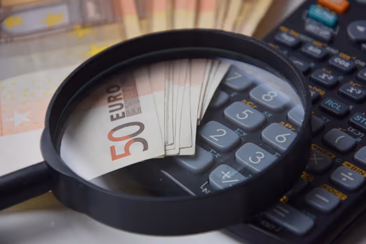 Hesap makinesi üzerinde büyüteç altında euro banknotları