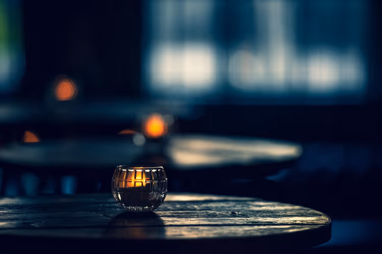 Kerze in einem Glas auf einem Tisch in einer dunklen Bar