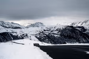 Geräumte Asphaltstraße windet sich durch die verschneiten Pyrenäen unter schwerem grauem Himmel