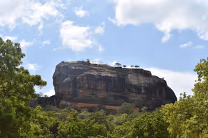 Felsenfestung Sigiriya ragt in Sri Lanka über dichten grünen Dschungel, blauer Himmel mit vereinzelten Wolken