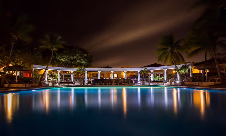 Işıklandırmalı ve palmiyeli tatil köyü gece havuzu