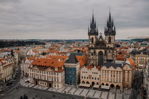 Gotische Doppeltürme der Teynkirche über Häusern mit roten Dächern am Altstädter Ring in Prag unter bedecktem Himmel