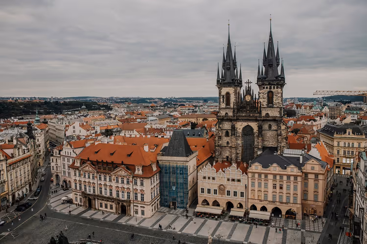 Gotische Doppeltürme der Teynkirche über Häusern mit roten Dächern am Altstädter Ring in Prag unter bedecktem Himmel