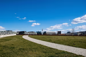 Geschwungener Kopfsteinpflasterweg über eine Wiese in Berlin, am Horizont moderne Bürogebäude und der Fernsehturm