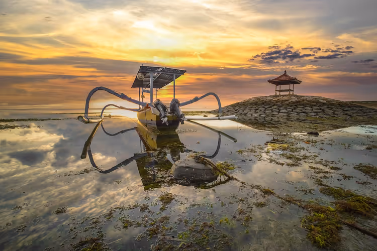 Soloppgang på Sanur-stranden med en båt og en paviljong