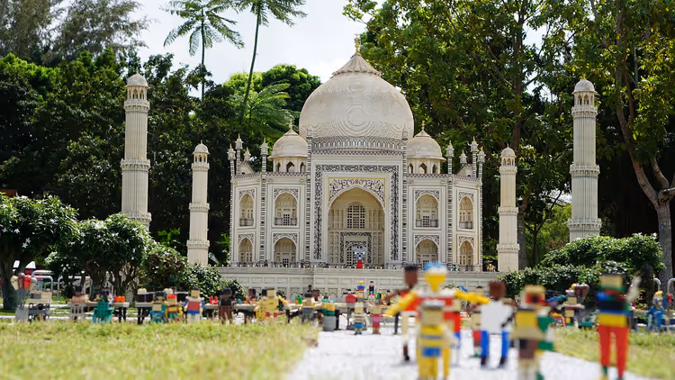 Taj Mahal als Modell aus Lego-Steinen mit kleinen Lego-Figuren im Vordergrund, umgeben von Palmen und Bäumen